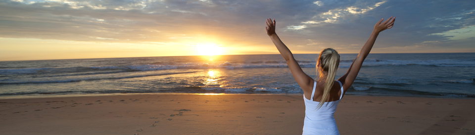 Girl with arms raised looking at sunrise